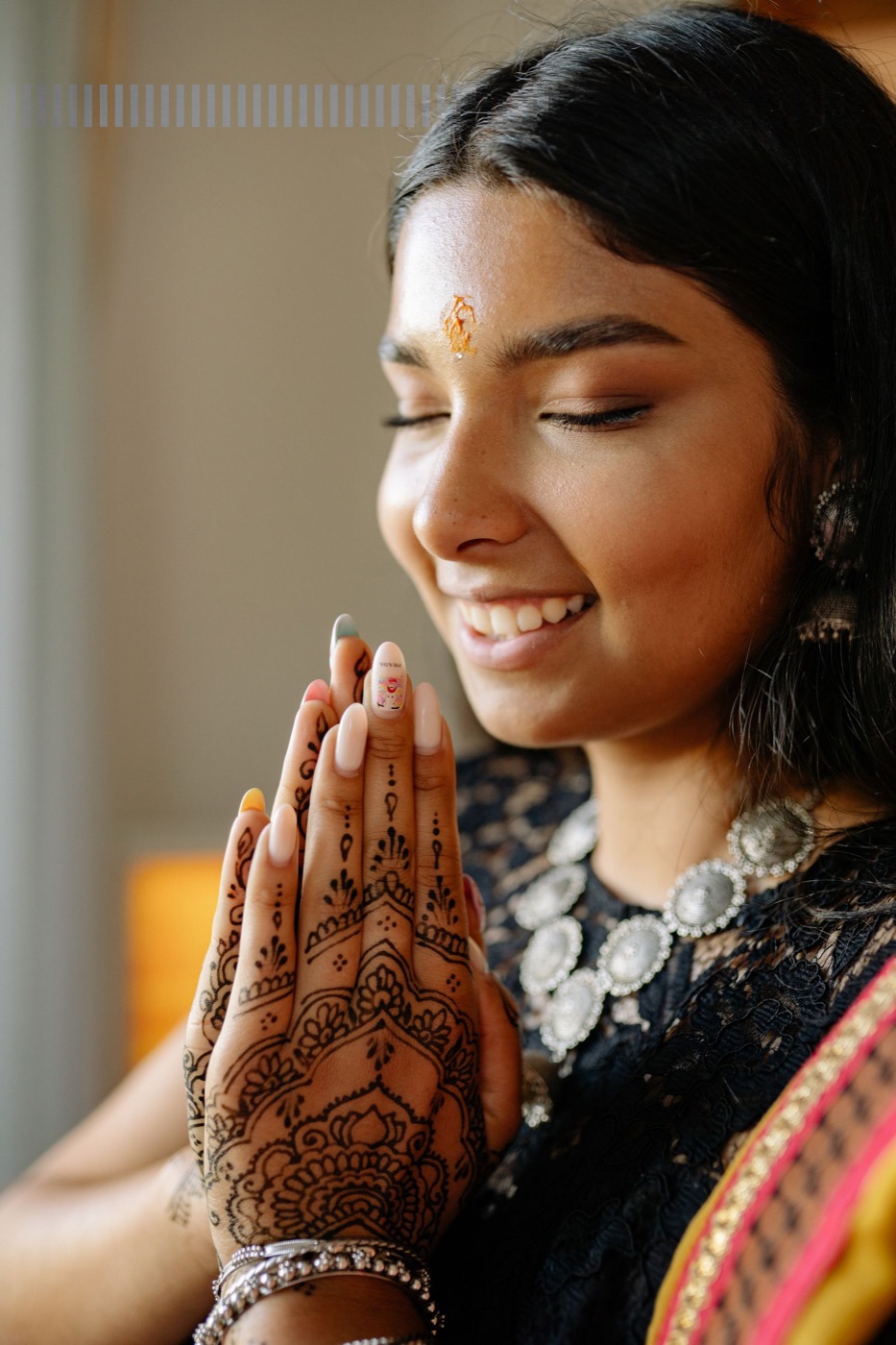 Indo-Caribbean beauty professional with nail art and henna